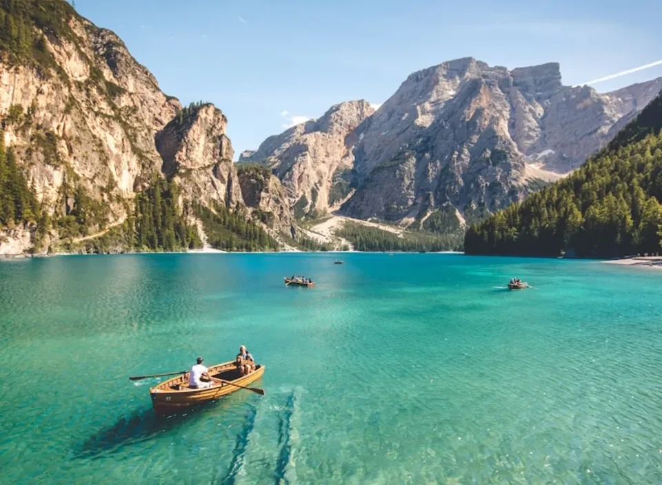 A wooden rowboat on a turquoise alpine lake below grey cliffs