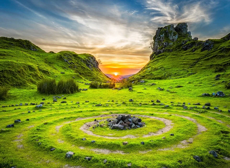 A stone circle set in a bright green meadow at sunset