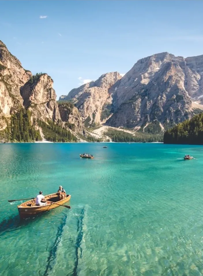 Rowboats moored on a turquoise lake under limestone peaks