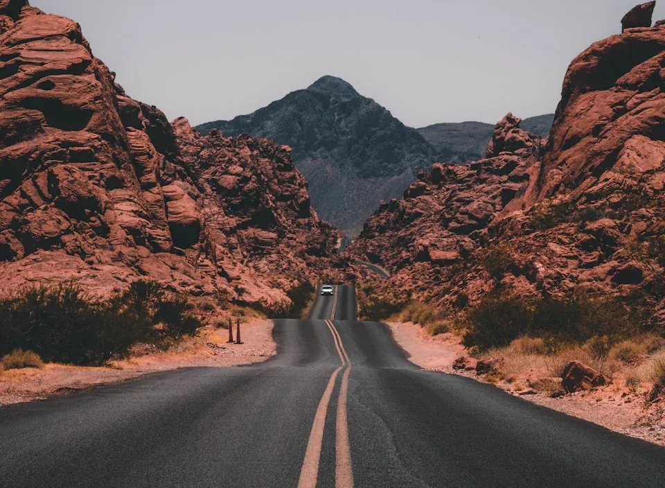 An empty highway running between red desert rock walls