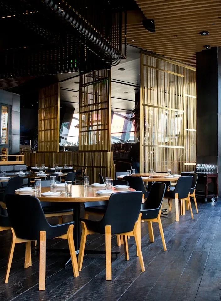 A warm restaurant interior with wooden tables and hanging lights