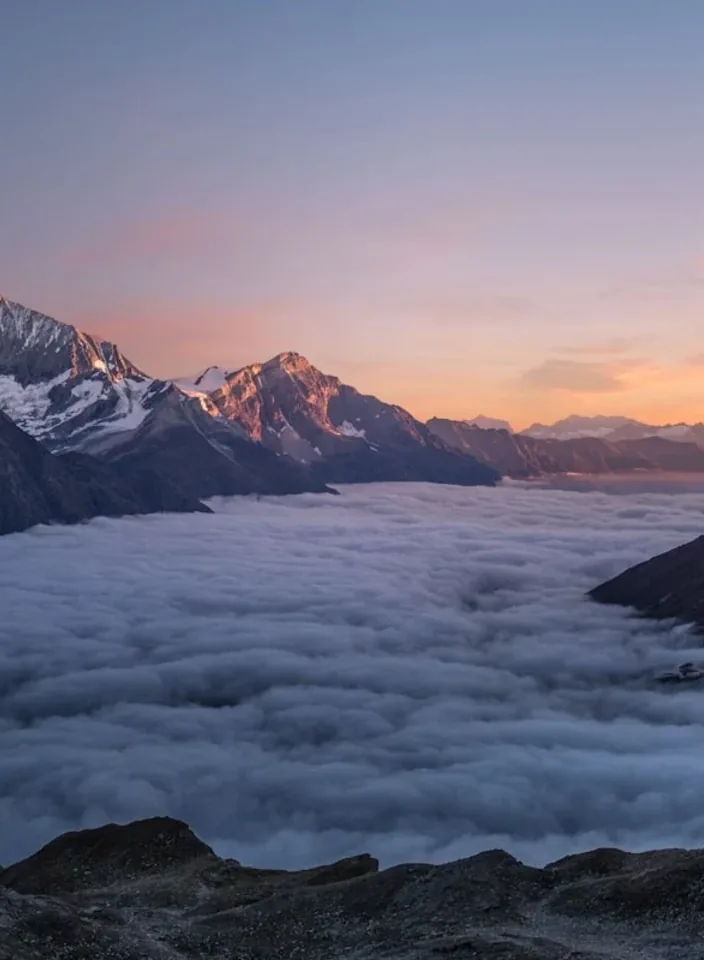 Snow mountains above a still cloud sea in cold morning light