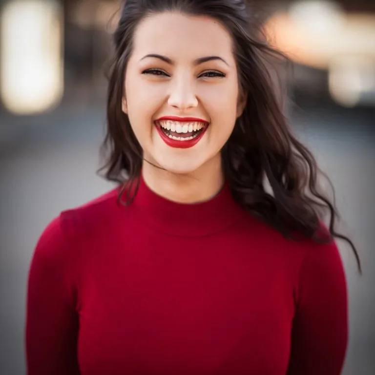 A woman in a red top laughing, the street behind her out of focus