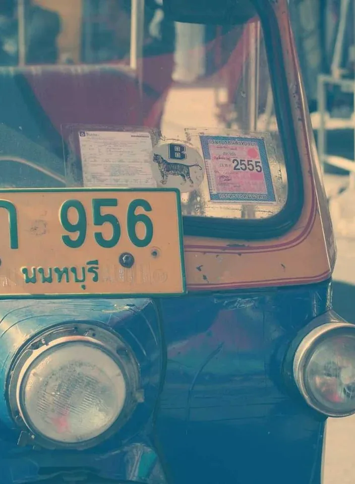 The front of a vintage teal car with a worn licence plate