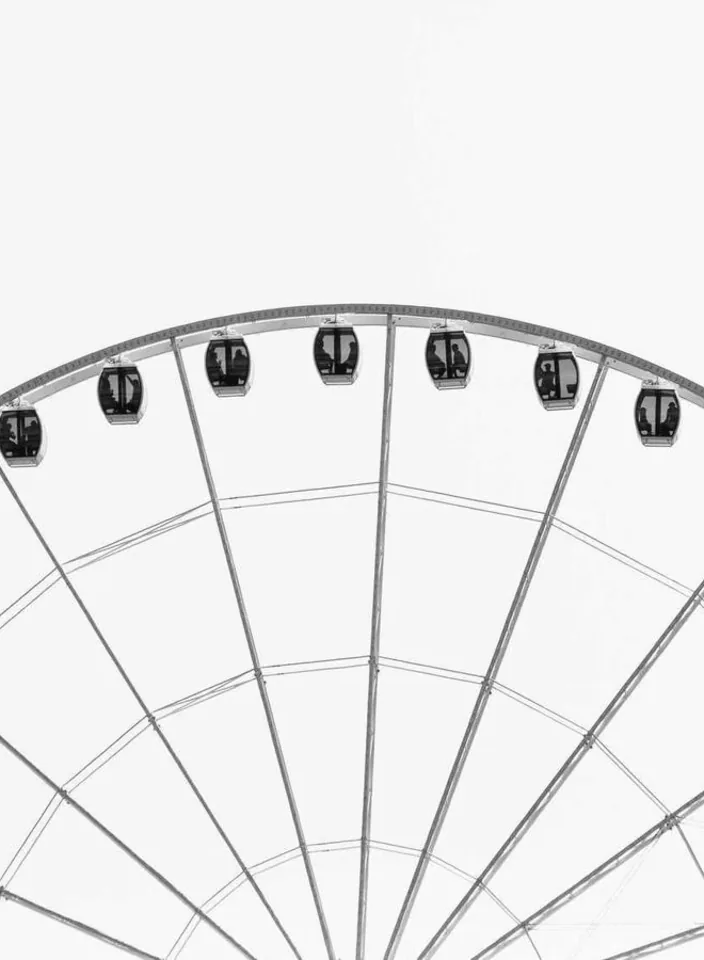 The white spokes of a ferris wheel against a blank pale sky